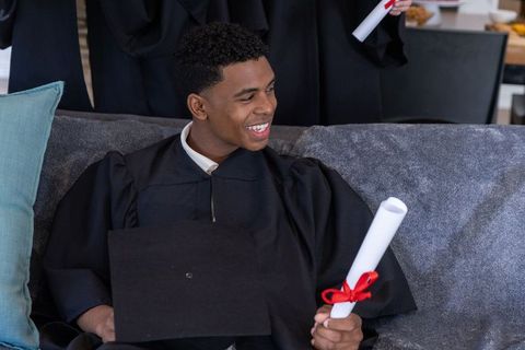 Happy Graduate Holding Diploma and Cap Surrounded by Peers