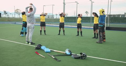 Male field hockey team stretching during warm-up session