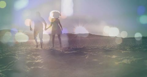 Couple walking hand in hand on sandy beach at sunset, silhouette romance with lens flare