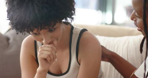 African american woman receiving comfort from friend on cozy living room sofa