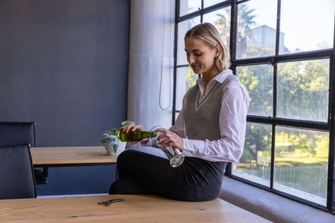 Woman Pouring Wine in Modern Office Environment