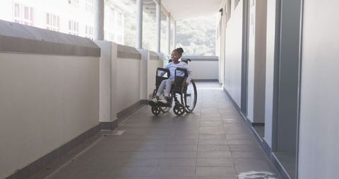 Young girl in wheelchair navigating sunny school corridor