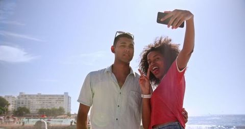 Smiling Biracial Couple Taking Selfie at Sunny Beach Promenade - Download Free Stock Images Pikwizard.com