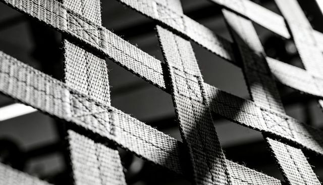 Monochrome nylon webbing lattice with stitched xs, frayed edges and high-contrast texture