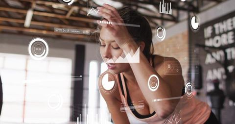 Young woman pausing during intense gym workout with augmented reality fitness overlays