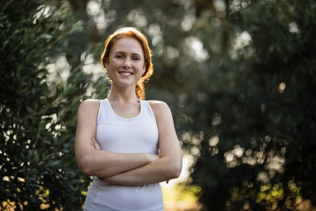 Confident young woman standing by trees at farm - Download Free Stock Photos Pikwizard.com