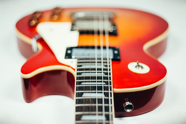 Close-up angle on vibrant red electric guitar highlighting strings, body, and control knobs. Perfect for use in musical instrument advertisements, music websites, online marketplaces for musical gear, graphic designs requiring music themes, or educational materials related to music learning.