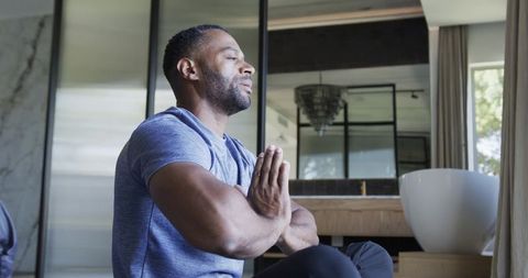 Man practicing mindful meditation by freestanding bathtub in minimalist home interior