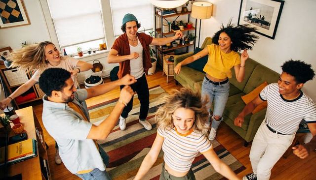 Young friends dancing in colorful living room capturing joyful movement and party energy