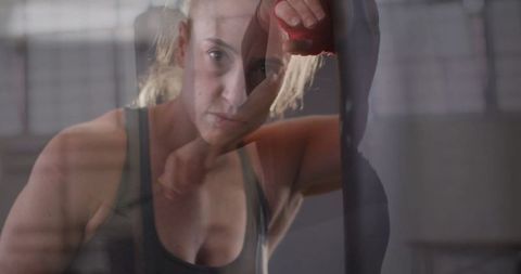 Determined Woman Training Punching Bag in Gym