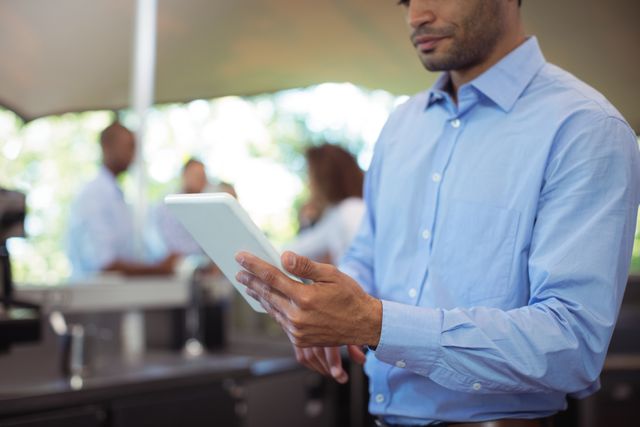 Mid-section of waiter using digital tablet at outdoor cafÃ©