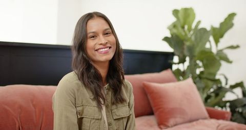 African american woman smiling on velvet sofa in contemporary minimalist living room