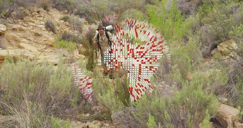 Male adventurer traversing rocky terrain with digital distortion overlay