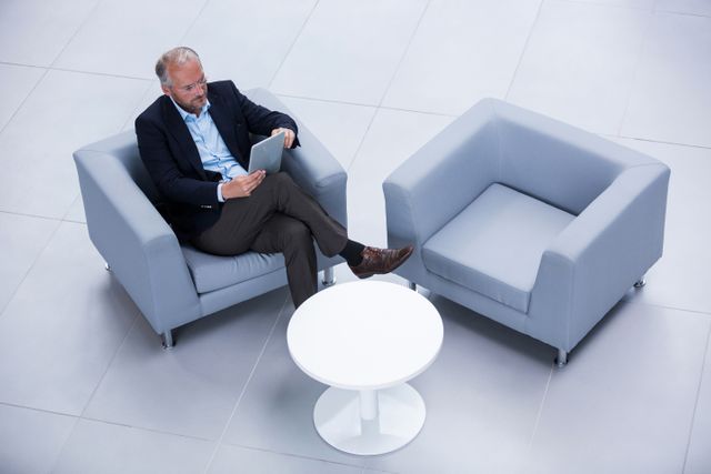 Businessman sitting on chair using digital tablet in office