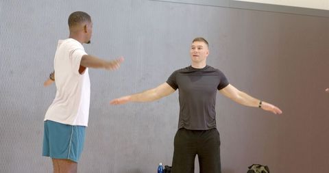 Fitness trainer leading arm stretch in gym group workout session with water bottle nearby