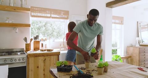 Couple Engaging in Gardening Paper Pots Inside Bright Farmhouse Kitchen
