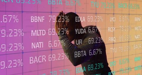 Stressed trader holding head against neon stock data wall silhouette backlit