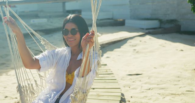 Relaxed Woman Enjoying Swing on Beach in Sunny Weather, Wearing Sunglasses - Download Free Stock Images Pikwizard.com