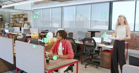 Young professional typing at open-plan office desk with augmented reality analytics overlay