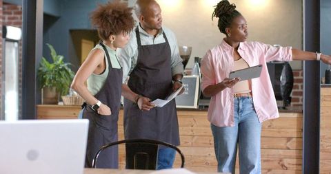 Cafe manager directing barista team with tablet during morning shift briefing