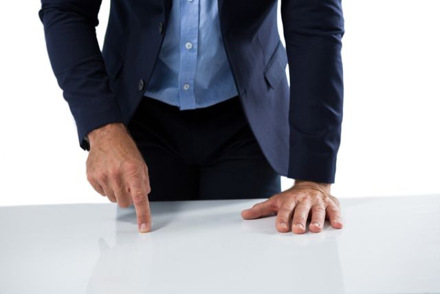 Businessman in a suit interacting with an invisible screen on a table. Ideal for use in business, technology, and innovation-related content. Suitable for illustrating concepts of modern office environments, professional interactions, and digital advancements.