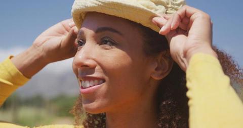 Smiling Woman Adjusting Hat Outdoors - Download Free Stock Images Pikwizard.com