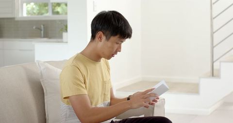 Teen reading letter on couch in tranquil indoor setting