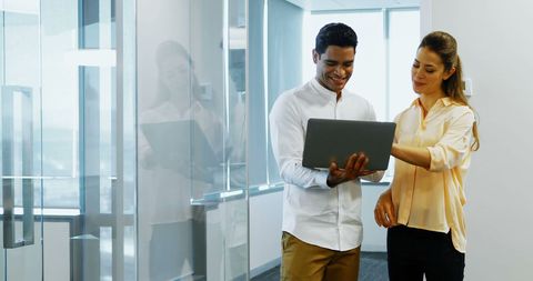Collaborative Team Discussing Project on Laptop in Modern Office