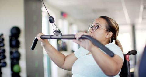 Woman with Paraplegia Using Cable Machine in Gym for Rehabilitation