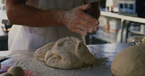 Baker Kneading Dough with Flour-Dusted Hands on Rustic Table