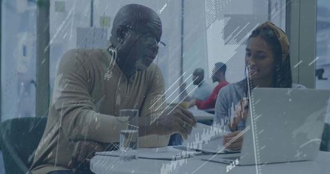 Senior mentor guiding young professional at modern office workspace