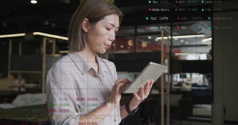 Businesswoman Analyzing Financial Data on Tablet in Modern Office Environment