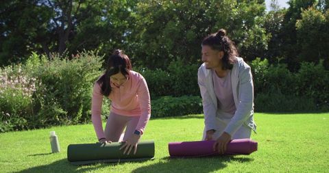 African american couple rolling yoga mats on sunny park lawn for outdoor fitness