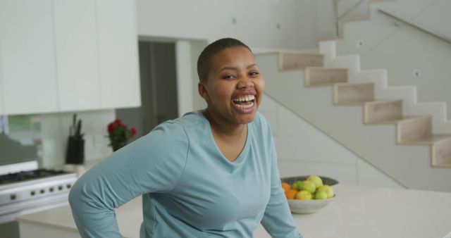 Portrait of smiling african american plus size woman looking at camera in kitchen. domestic lifestyle, enjoying leisure time at home.