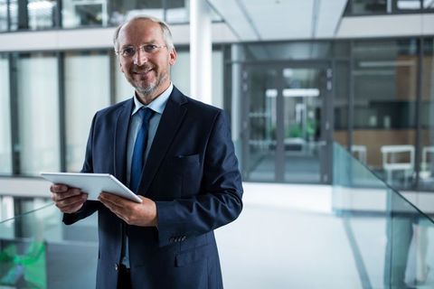 Senior Business Executive with Tablet in Bright Office Atrium