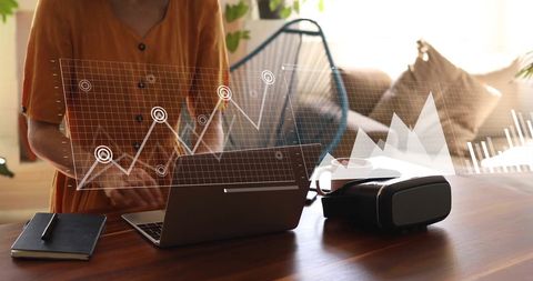 Woman analyzing financial data on laptop with virtual interface