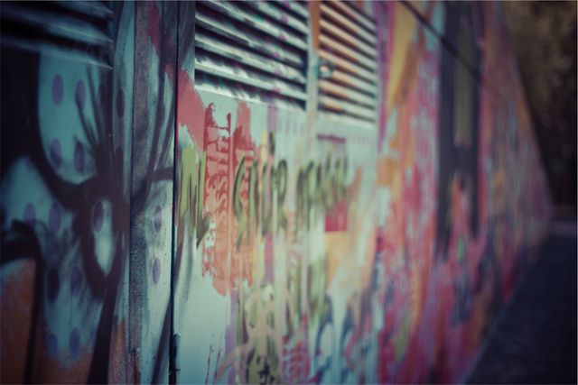 Photo showcases graffiti art in rich, varied colors on an urban wall from a close-up perspective. The painted wall depicts street culture and creative self-expression in an urban environment. Useful for themes around urban art, public artwork, contemporary street culture, and creative backgrounds.