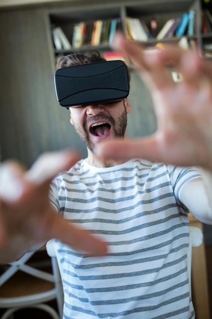 Excited man using virtual reality headset in coffee shop