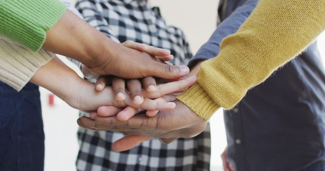 This image depicts a diverse group of people stacking hands, symbolizing teamwork and unity. It may be used to illustrate themes of partnership, diversity, collaboration, and community spirit in both business and social contexts.