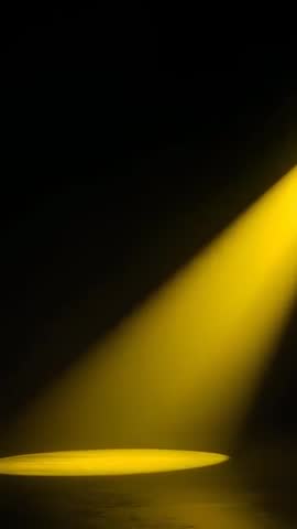 Vertical video casting yellow spotlight slanted beam widening round pool on stage