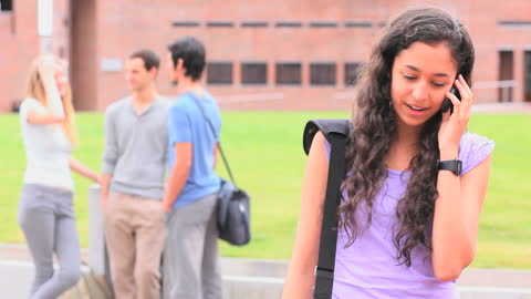 Student Talking on Phone with Friends in Background at Campus