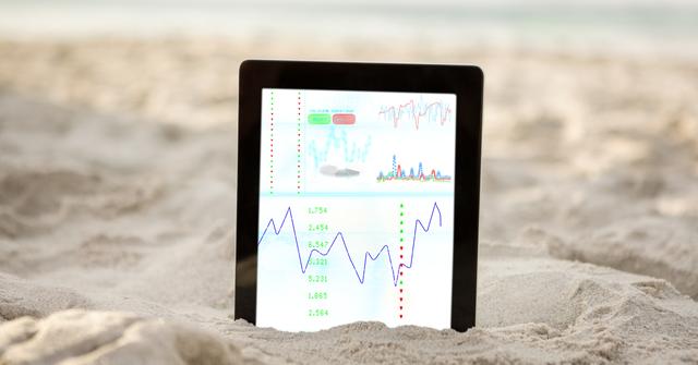Business data on digital tablet embedded in sand, symbolizing remote work or combining work with relaxing beach environments. Useful for concepts around mobile business, work-life balance, vacation productivity, and technology outdoors.