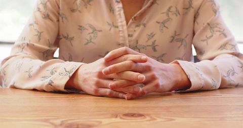 Thoughtful Individual Clasping Hands Wearing Bird Pattern Shirt