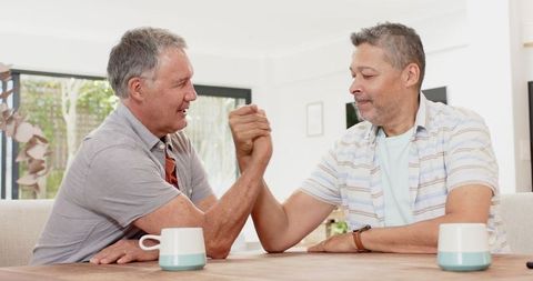 Diverse Male Friends Arm Wrestling at Wooden Table