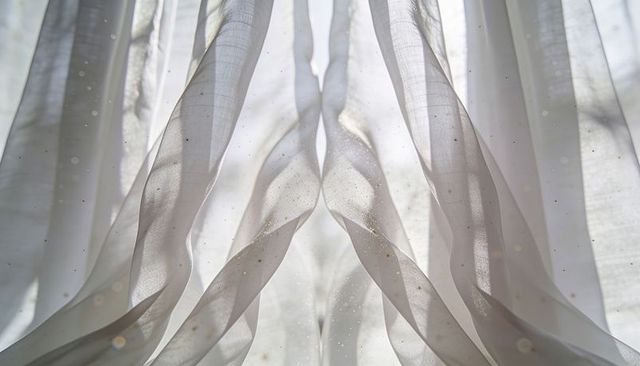 Billowing sheer curtains backlit by sunlight revealing floating dust and soft texture