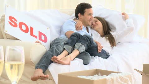 Happy Couple Celebrating New Home Purchase on Couch