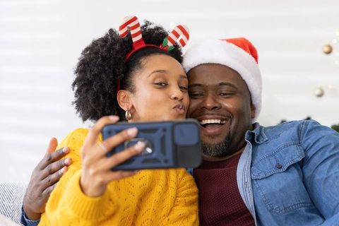African american couple taking festive christmas selfie wearing santa hat and headband