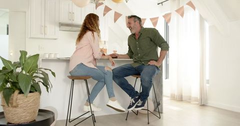 Smiling Couple Relaxing at Kitchen Counter Taking Selfie