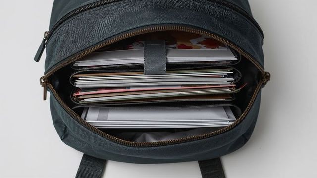 Open backpack on desk, featuring laptop and documents
