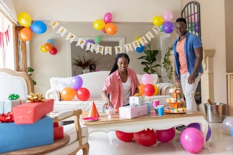 African american couple decorating living room for birthday party with balloons, gifts